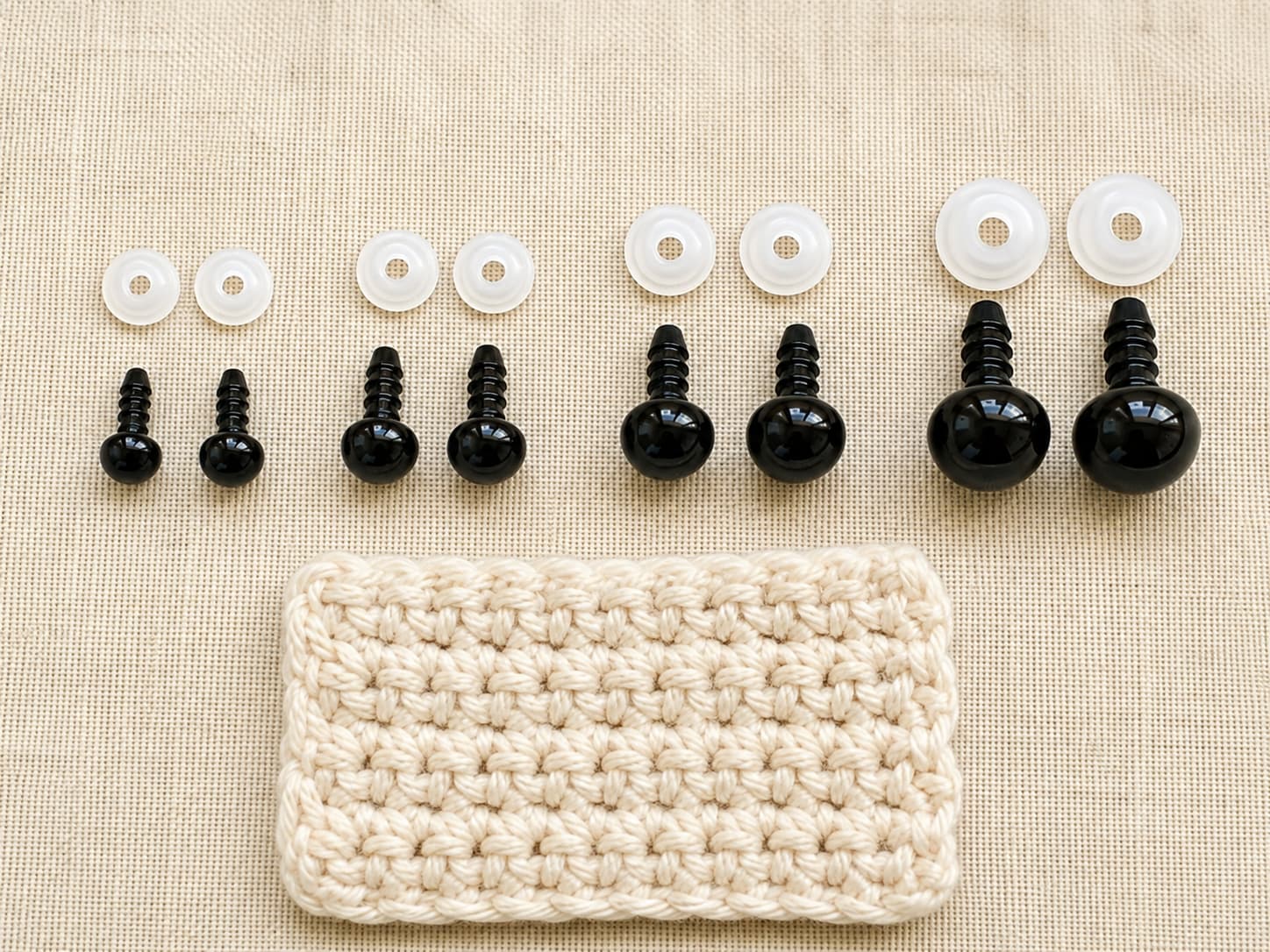 Four common amigurumi safety-eye sizes arranged from 6 mm to 12 mm beside a small crochet swatch for scale.
