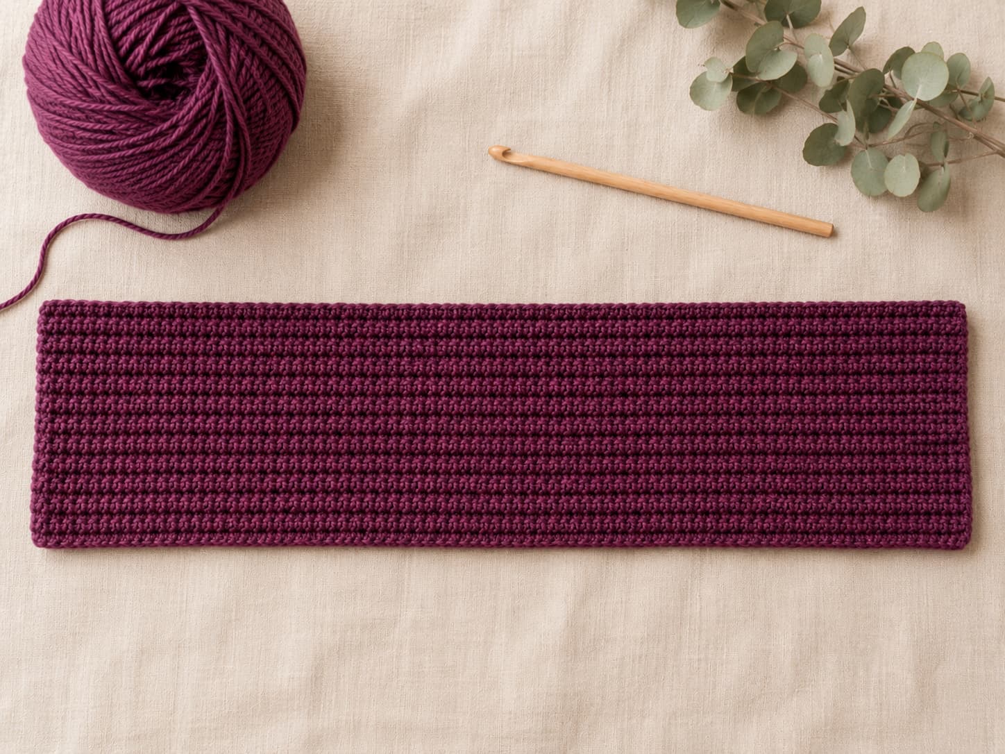 Long plum-berry crochet rectangle worked in back-loop half-double crochet with straight edges, twelve rows, and a visible flexible rib texture.