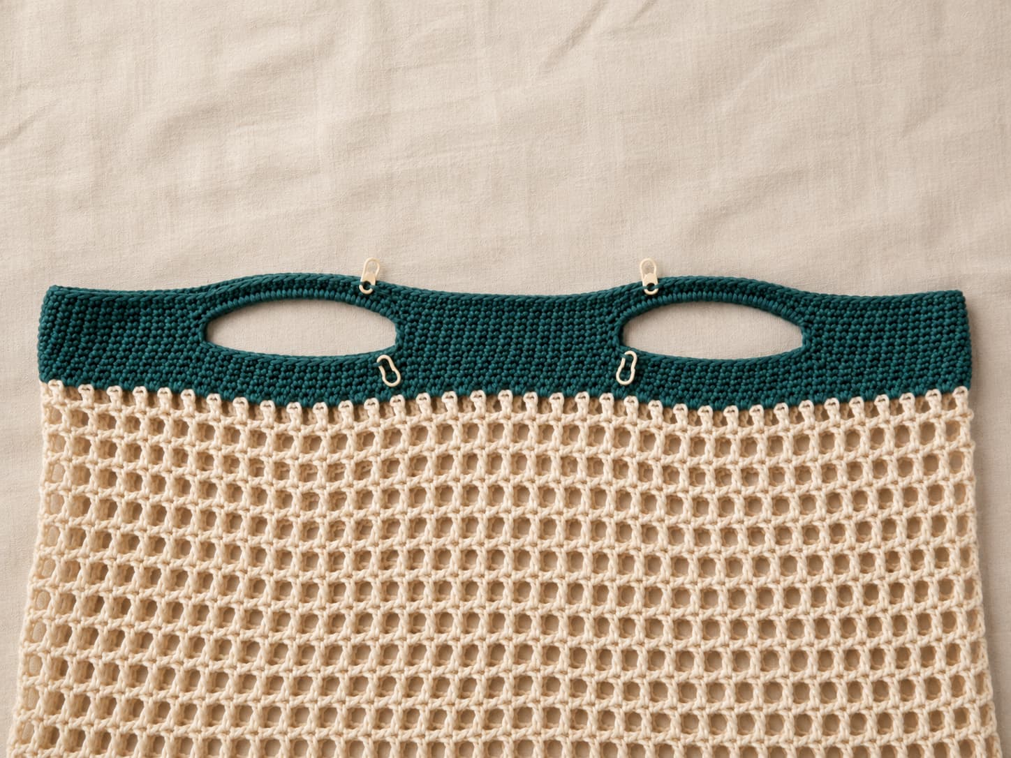 Deep jade-teal solid top band on a crochet market bag with four stitch markers showing two symmetrical eighteen-stitch handle openings.