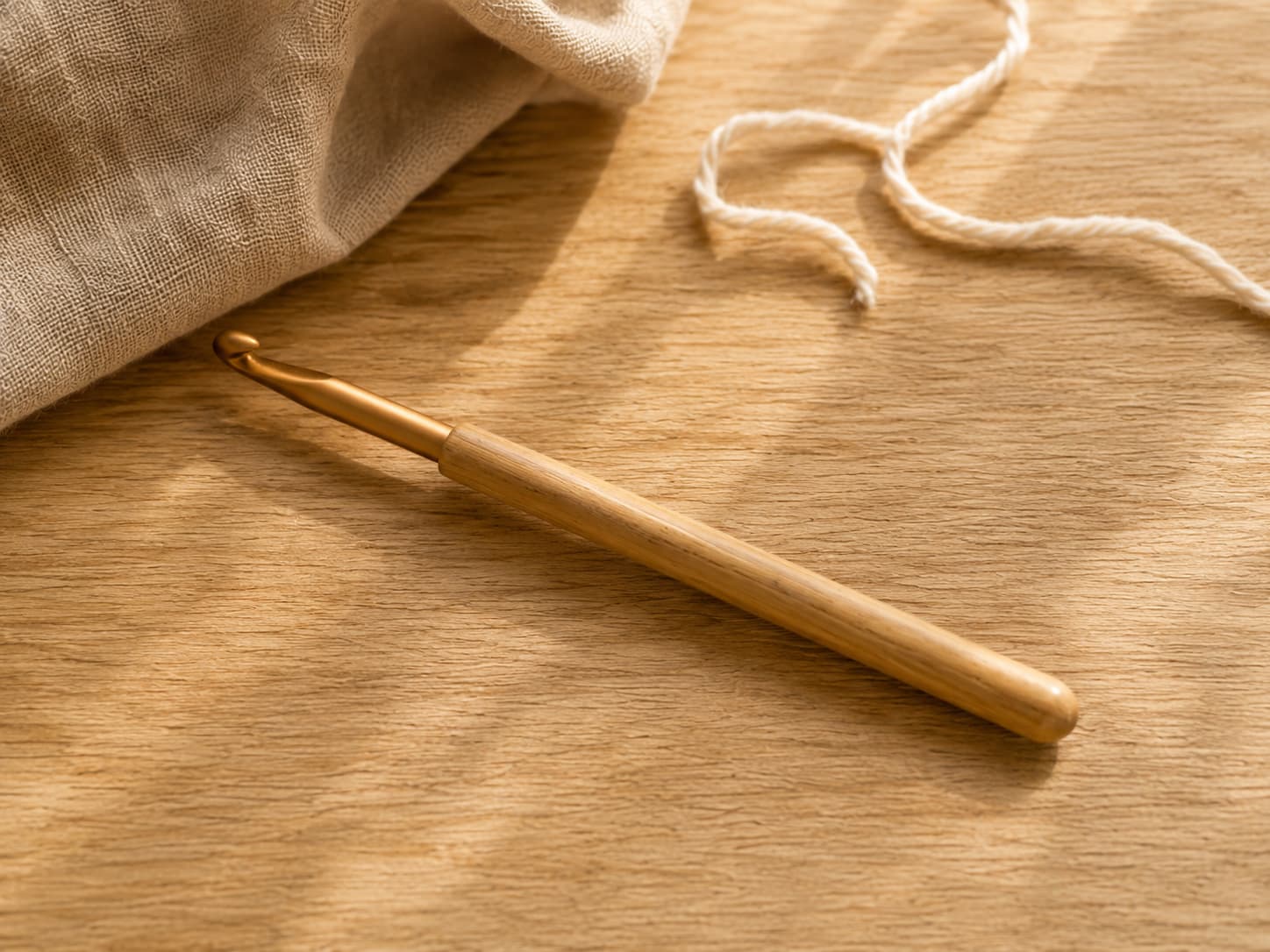Bamboo, polished wood, and metal knitting needles with a circular cable join shown in close-up.