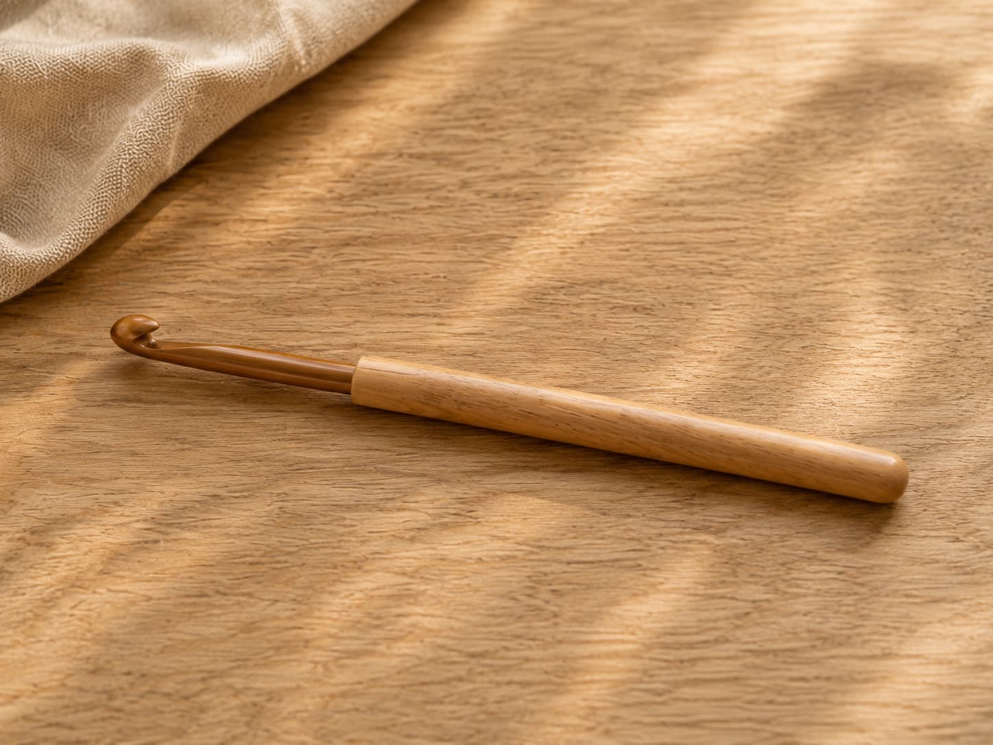 Close-up of one crochet hook showing the head, throat, shaft, grip, and handle against a neutral background.