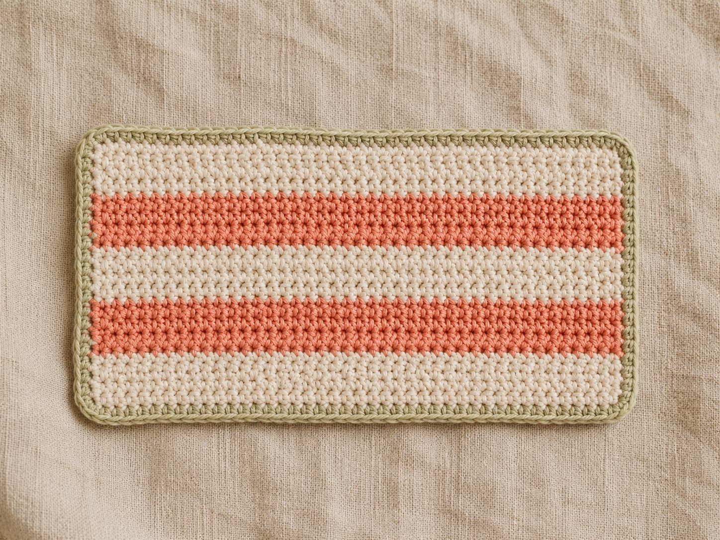 Soft-oatmeal rectangular single crochet coaster with warm-coral four-row stripes and a neat contrasting border on natural linen.