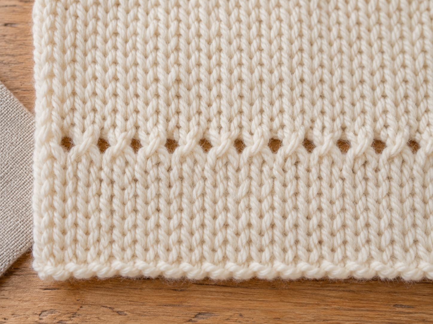 Close-up of Cloud Nine Stitch showing smooth stockinette rows with a delicate horizontal eyelet line in soft cream yarn.