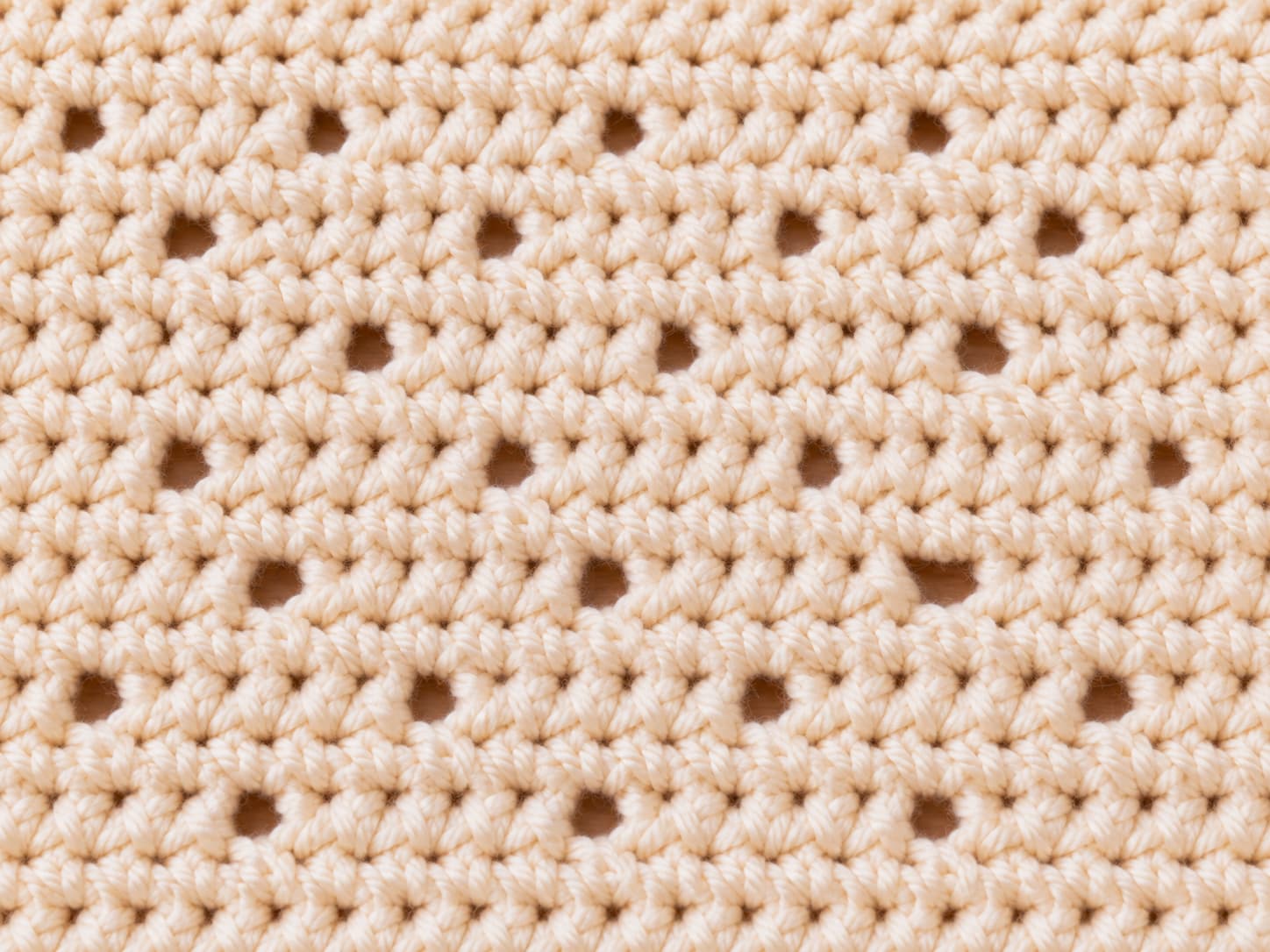 Close-up of the Garden Path crochet stitch showing staggered chain-two spaces and solid single crochet rows in warm cream yarn