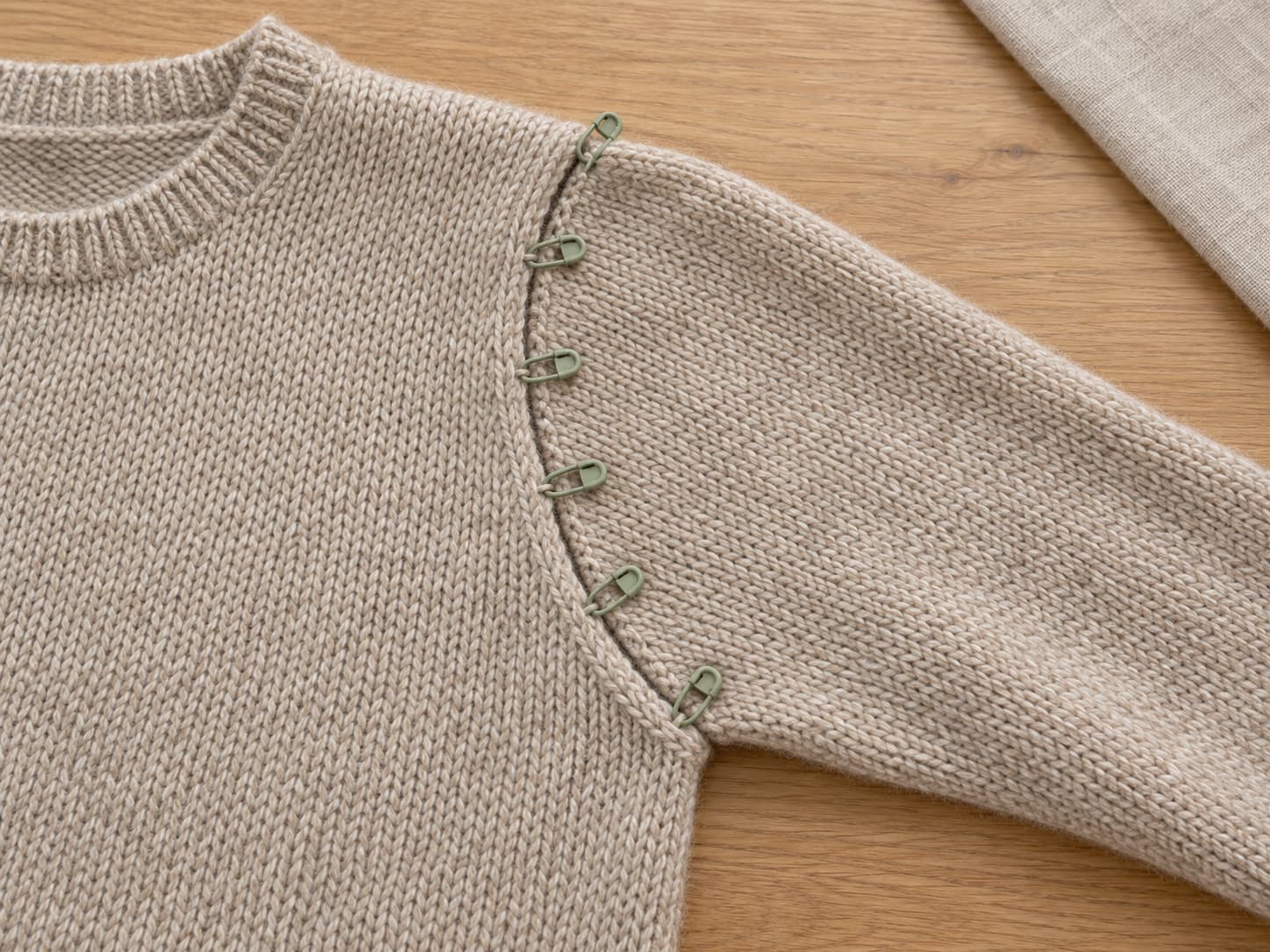 Knitted sleeve top aligned to an armhole edge with locking stitch markers